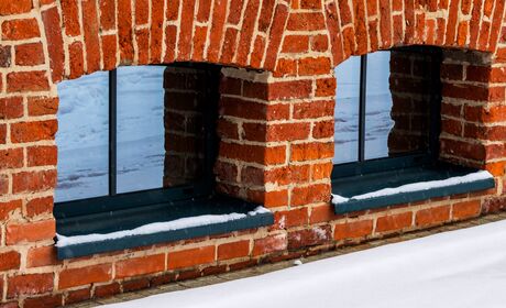 Dunkle, kleine Kellerfenster aus Aluminium in Ziegelmauer