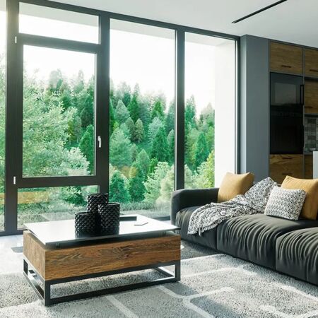 Wohnzimmer mit Aluminium Panoramafenster in dunkler Farbe und Holzzusätze mit moderner Küche hinten und Aussicht auf Wald